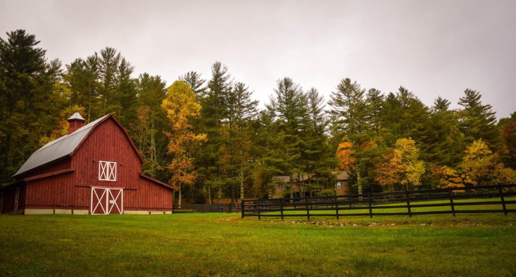 Red barn and an open field with trees behind.