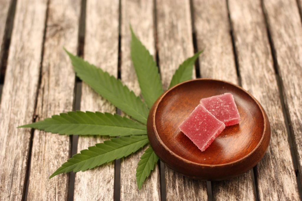 Tray with gummy candies on top of a table with a hemp leaf