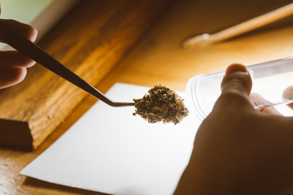 A person placing cannabis in a tube bottle