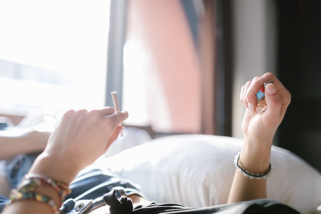 A person holding a cannabis join and a lighter