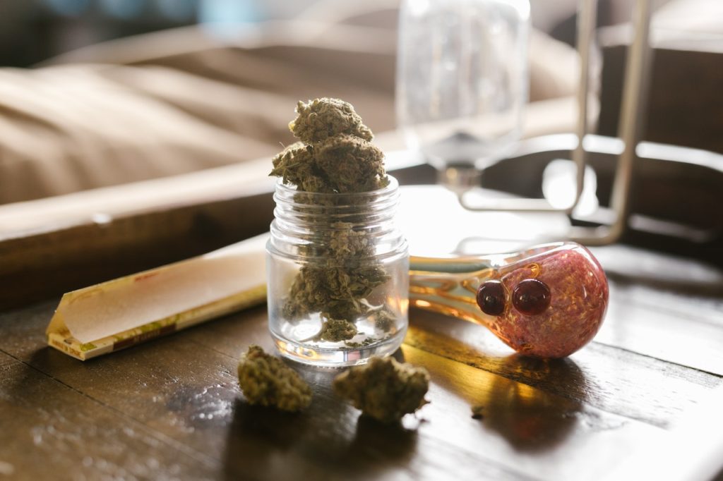 A jar of cannabis and a glass pipe