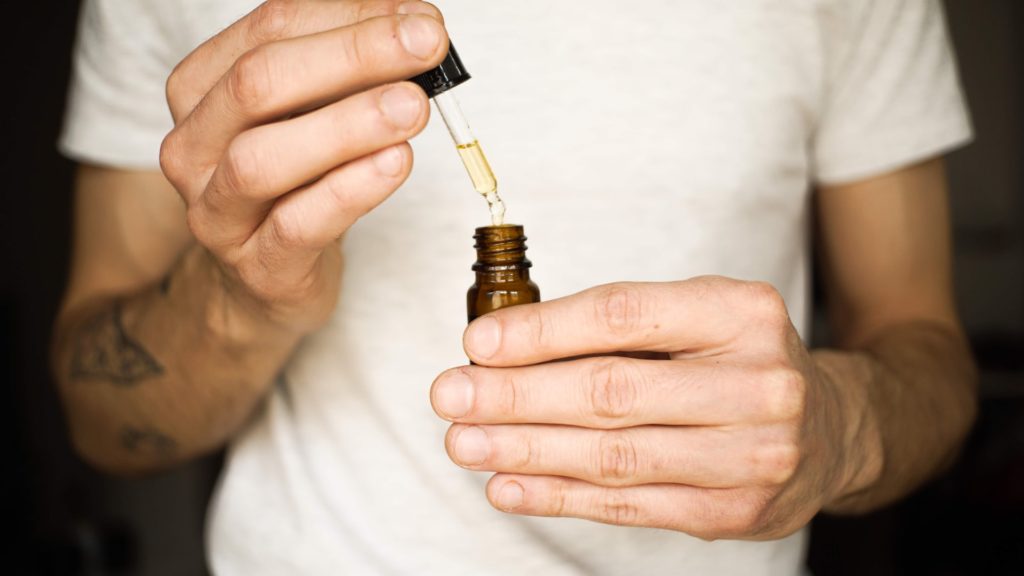 A man holding the dropper of THC-O acetate tincture