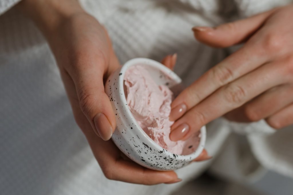 A woman scooping up topical CBD cream