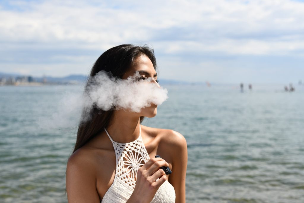 A woman vaping by the ocean