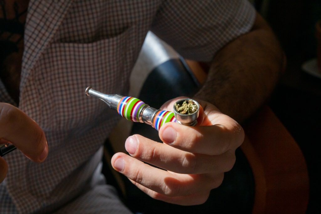 Person packing a pipe with cannabis