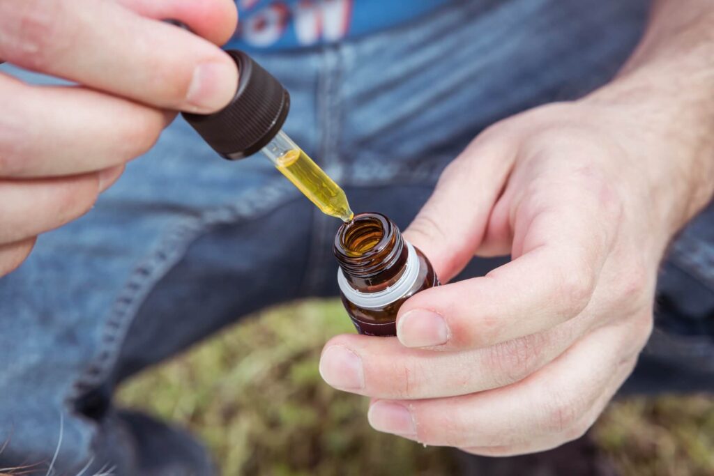 Man holds dropper of CBD oil